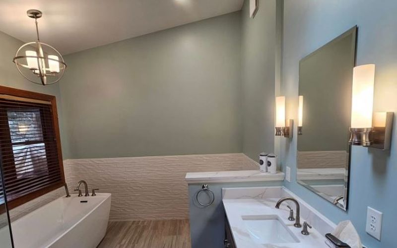 Remodeled bathroom with freestanding tub, quartz vanity and wall sconces