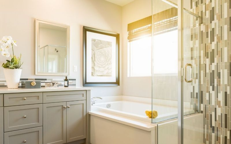 Glass-enclosed shower with a vertical mosaic tile strip