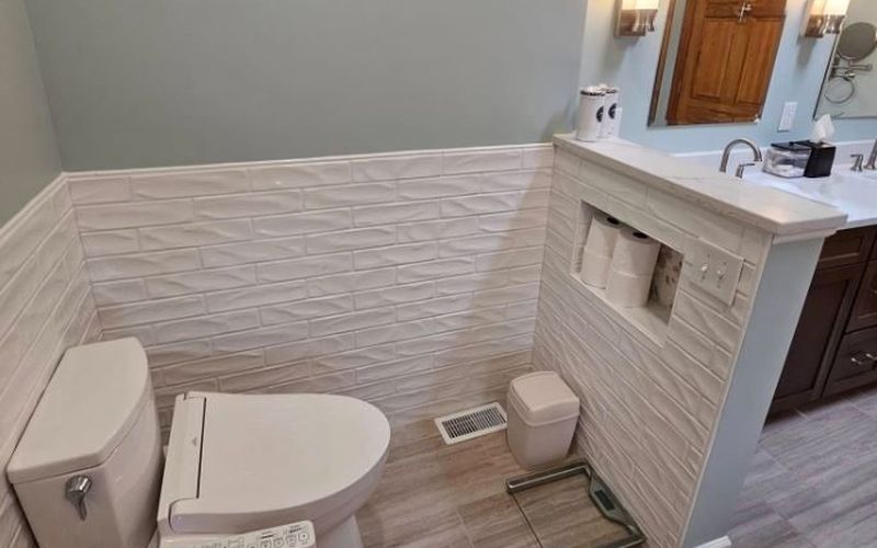 Compact bathroom with textured wainscot tile and a tiled half wall