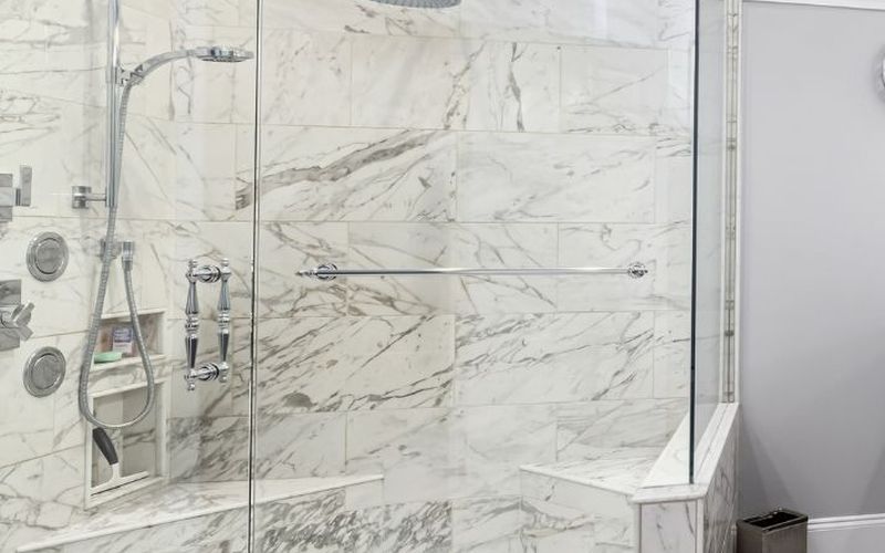 Walk-in shower with marble-look walls and frameless glass