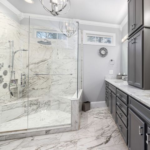 Marble-look shower with frameless glass enclosure and grey vanity